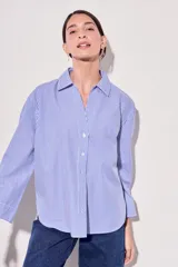 Camisa celeste con rayas verticales blancas, de corte clásico, con cuello camisero y mangas largas.