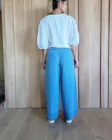 Pantalón de jean azul de corte palazzo con cintura alta y detalle de costuras horizontales en el ruedo.