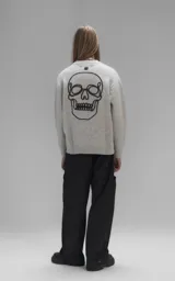 Sweater de cuello redondo color gris melange, con diseño de punto texturado y bordado en relieve con las letras 'Lx.' en el pecho. Presenta terminaciones en punto rib en cuello, puños y ruedo.