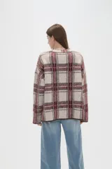 Sweater de punto jacquard con diseño a cuadros en tonos beige y bordó, de corte holgado, cuello redondo y mangas largas.