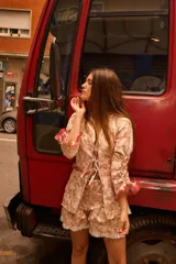 Camisa larga tipo smock de brocato con estampado floral en tonos rosados, manga larga con cordones ajustables y detalles de flecos en los bordes.
