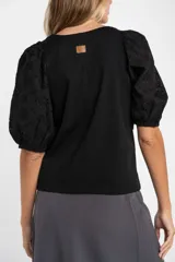 Remera negra de algodón con cuello redondo y mangas globo cortas confeccionadas en tela con detalle de broderie.