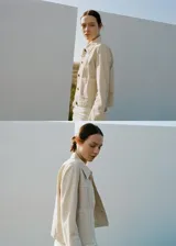 Chaqueta de algodón estilo tejano en color beige, con cuello camisero, manga larga, dos bolsillos de parche en el frente y cierre delantero de botones.