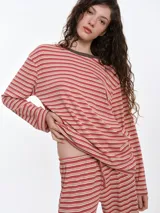 Remera de dormir de corte oversize, confeccionada en algodón con estampado de rayas horizontales en tonos rosa y crema. Presenta escote redondo con cuello de rib en color marrón oscuro y mangas largas.