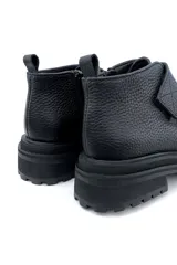 Bota corta negra de cuero con ajuste de velcro y suela track.