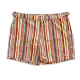 Short de baño con estampado geométrico en tonos tierra, naranja y violeta. Cuenta con pretina fija, hebillas metálicas laterales para ajuste, cierre frontal con botón a presión y tres bolsillos. Incluye interior con mesh hipoalergénico.