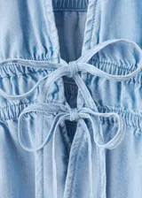 Top de denim suave color celeste con cuello halter, escote en V profundo y cordón ajustable en la cintura.