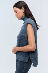 Chaleco de punto azul con cuello alto y diseño de trenzas.