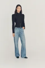 Jeans wide leg de tiro medio confeccionado en denim con efecto lavado, corte relaxed y diseño de pernera ancha. Cuenta con cinco bolsillos, trabillas en la cintura y cierre frontal con cremallera y botón metálico. Presenta aplicación de brillos en toda la prenda.