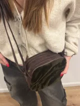 Bandolera de cuero marrón con panel frontal de piel sintética con estampado animal en tonos verde oliva y marrón. Tiene correa larga regulable, cierre superior con cremallera y forro interior.