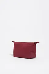 Neceser de diseño trapecio confeccionado en nylon color bordó, con cierre superior y logo de la marca estampado en dorado en el frente.