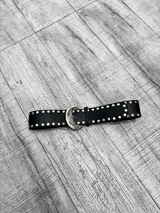 Cinto de cuero sintético negro con hebilla metálica plateada y tachas redondas plateadas.