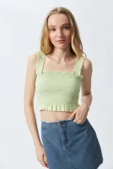 Crop top cuadrillé sin mangas con volados en la cintura.