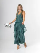 Vestido largo negro de seda italiana con diseño sin mangas de bretel ancho y escote en V profundo con detalles de paillettes plateados. Presenta múltiples capas con volados y bordes deshilachados que aportan movimiento y una caída fluida.