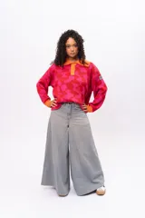 Buzo de tejido de punto con diseño geométrico en tonos fucsia y rojo, cuello tipo polo con cierre de botones y puños en color naranja contrastante. Presenta un corte holgado y oversize.