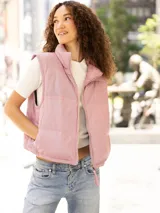 Chaleco puffer de cuero de cordero perforado en color gris. Presenta un diseño acolchado con cuello alto, cierre frontal de cremallera y ajuste en el bajo con cordones elásticos.