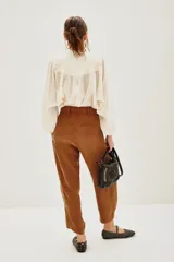 Pantalón sastrero de tiro alto, color blanco, confeccionado en cupro y viscosa. Presenta pinzas delanteras, bolsillos y ajuste elástico en el tobillo.