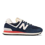 Championes urbanos New Balance modelo 574, color azul marino con detalles en blanco y una franja roja en la entresuela, confeccionados con capellada de malla y gamuza, y suela de goma.