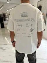 Remera oversize blanca de manga corta, con diseño gráfico estampado en la espalda en tonos grises que incluye la frase "The Bright Future" y varios motivos abstractos.