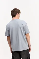 Remera oversize de manga corta, color gris, con calce amplio y estampa frontal con letras en relieve visual y marca Mistral.