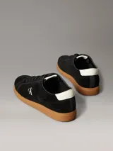 Zapatillas Calvin Klein de perfil bajo elaboradas en ante negro, con suela cupsole de goma marrón. Presentan detalles en contraste de color blanco en el talón y la lengüeta, además del monograma 'ck' bordado en el lateral.
