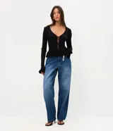 Pantalón baggy de jean azul con tiro medio, corte holgado, recortes en las rodillas y llavero decorativo con perlas y dije de corazón.