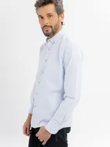 Camisa de manga larga con diseño de rayas finas verticales en color azul y blanco. Presenta cuello con botones, cierre frontal con botonadura y un bolsillo en el pecho.