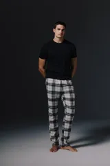 Pantalon de pijama con estampado de cuadros en tonos blanco, negro y gris, con cintura elástica y cordón ajustable.