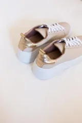 Championes urbanos color beige con detalles dorados en el talón y plantilla con la inscripción 'BRIDA'.