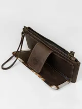Billetera porta celular confeccionada en cuero marrón con detalle de pelo vacuno con estampado animal print tipo vaca en tonos blancos, marrones y negros. Cuenta con correa de muñeca y cierre superior.