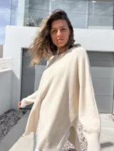 Sweater oversize de tejido de punto color crudo, con cuello redondo, manga larga con puños acanalados y detalle de costura vertical central. Presenta un diseño holgado con aberturas laterales en el ruedo.