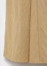 Vestido midi de corte evasé en color beige, con cuello en pico y manga corta. Presenta un diseño con costuras verticales decorativas y cierre de cremallera en la parte posterior.