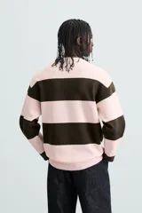 Jersey de punto con diseño de rayas horizontales anchas en color rosa claro y marrón oscuro. Presenta cuello redondo, manga larga y terminaciones en rib.