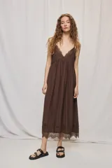 Vestido largo negro de silueta fluida, con breteles finos y escote en V con detalles de encaje. Presenta frunce bajo el busto y terminación de encaje en el ruedo.