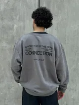 Buzo gris con cuello redondo, mangas largas y puños y bajo acanalados. Estampado frontal con el logo "Osten" y la frase "A mindset of becoming".