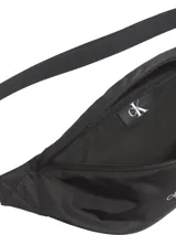 Riñonera negra de poliéster reciclado con logo Calvin Klein Jeans estampado en gris en el frente. Tiene correa ajustable con clip.