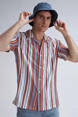 Camisa de manga corta con cuello solapa y cierre frontal con botones. Presenta un estampado de rayas verticales en tonos marrón, azul y blanco.