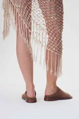 Sandalias bajas de cuero color marrón con detalles de tachas metálicas.