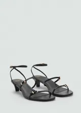 Sandalia de tacón kitten color negro con diseño de tiras finas, cierre de hebilla ajustable en el tobillo y detalle de hebillas metálicas doradas en las tiras frontales.