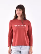 Remera de manga larga color rojo ladrillo, con estampado frontal en blanco que dice "you can be WHATEVER you want to be".