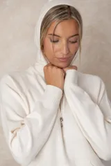 Buzo de punto negro con capucha, cordones ajustables con terminales metálicos, mangas raglán y bolsillo tipo canguro frontal.