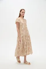 Vestido midi de viscosa color beige con estampado floreado, diseño amplio de corte en capas, mangas cortas con vuelo y escote en V.