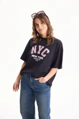 Remera de algodón negra de manga corta y corte holgado, con estampa frontal con la inscripción "NYC New York The Big Apple City".