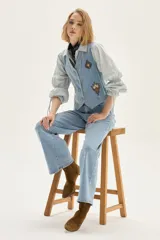 Chaleco de denim celeste con bordados decorativos en el frente, cierre de botones y corte entallado.