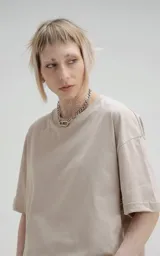 Remera de manga corta y cuello redondo, color beige claro, con calce boxy fit, caracterizado por ser ligeramente más corta y tener mangas amplias.