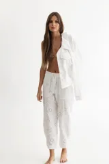 Pantalón babucha blanco de lino con bordados florales, pretina combinada con cierre y botón en el frente y elástico ancho en la espalda, ajuste en los tobillos con tiras y bolsillos aplicados.