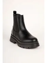 Bota de caña baja tipo Chelsea color marrón, con paneles elásticos laterales y suela track negra con plataforma dentada. Presenta textura en relieve en la parte trasera del talón.