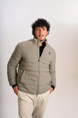 Campera puffer de corte clásico en color beige, con cierre frontal, cuello alto y puños elásticos. Presenta un diseño acolchado horizontal y un pequeño logo bordado en el pecho.