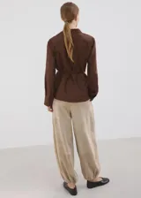 Camisa cruzada de color marrón, con diseño recto, cuello camisero, manga larga y cierre de lazo en la cintura con botones.