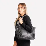 Cartera negra tipo tote bag con doble asa de hombro, cierre superior y detalles de correas con hebillas y cremalleras en los laterales.